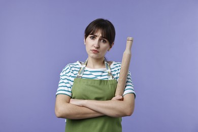 Photo of Upset woman with rolling pin on violet background