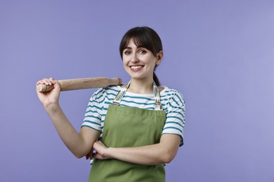 Photo of Happy woman with rolling pin on violet background