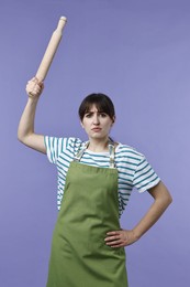 Photo of Angry woman with rolling pin on violet background