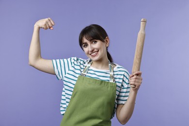 Photo of Woman with rolling pin showing strength on violet background