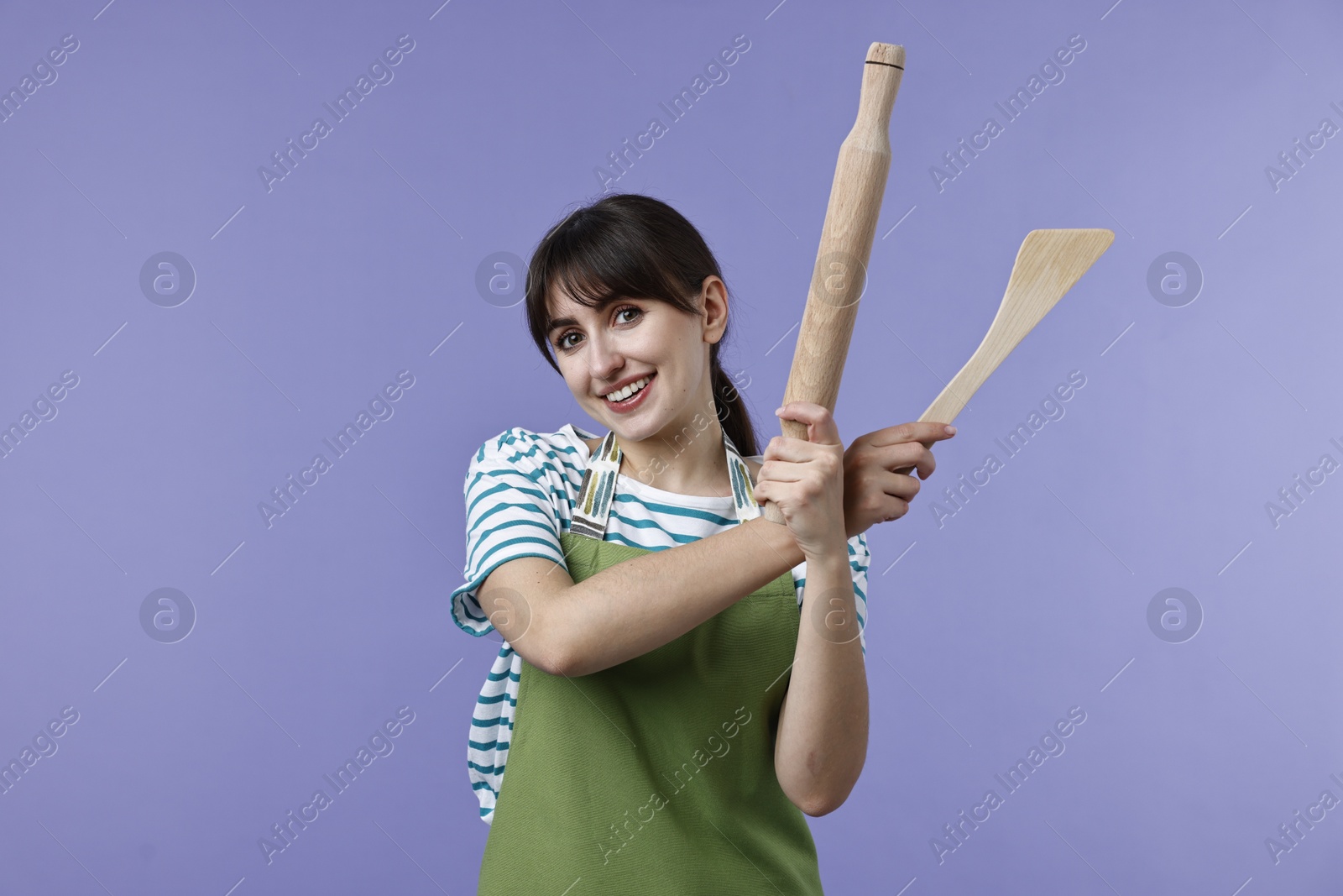 Photo of Woman with rolling pin and turner on violet background