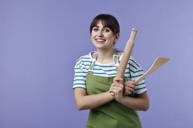 Photo of Woman with rolling pin and turner on violet background