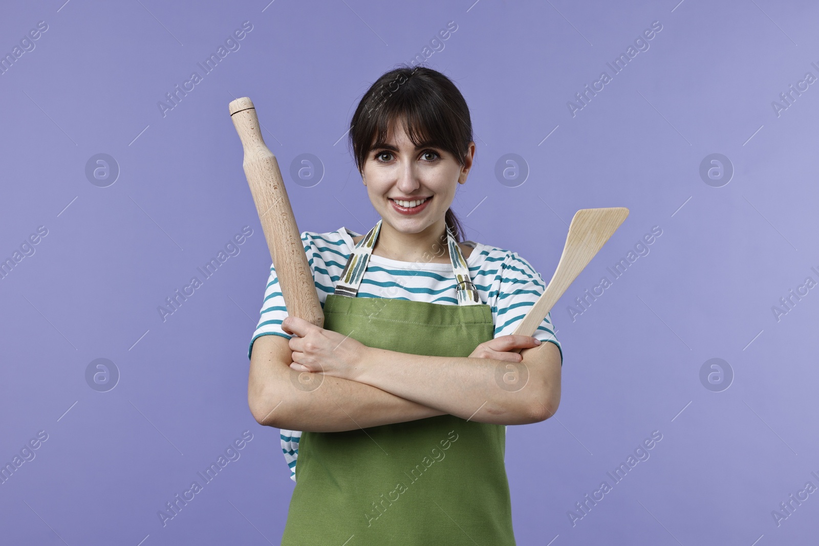 Photo of Woman with rolling pin and turner on violet background