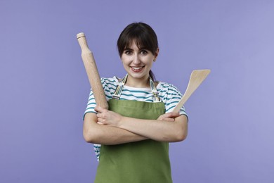 Photo of Woman with rolling pin and turner on violet background