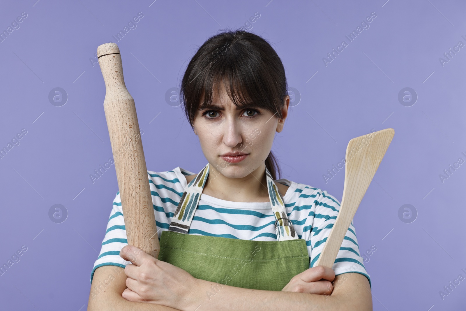 Photo of Woman with rolling pin and turner on violet background