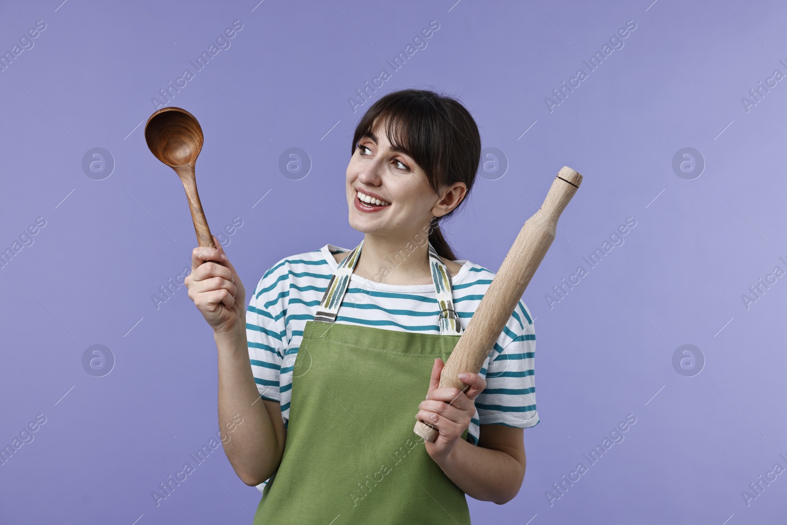 Photo of Woman with rolling pin and ladle on violet background