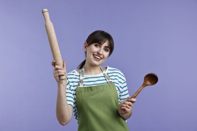 Photo of Woman with rolling pin and ladle on violet background