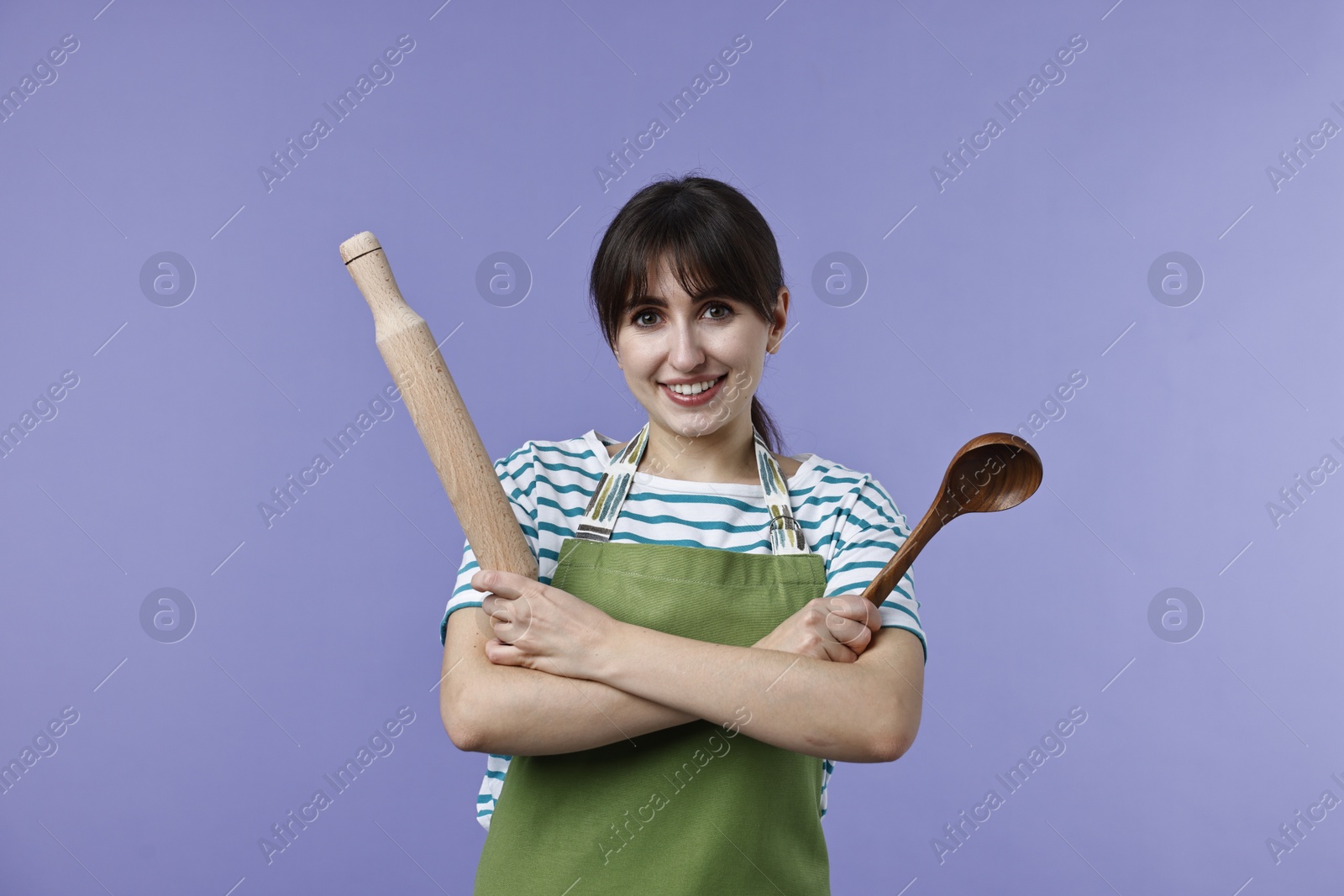 Photo of Woman with rolling pin and ladle on violet background