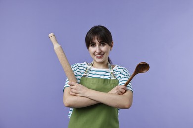 Photo of Woman with rolling pin and ladle on violet background