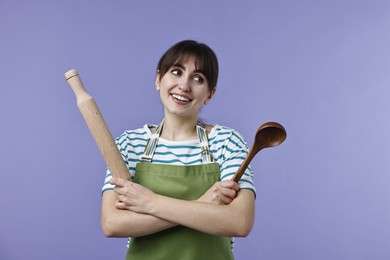 Photo of Woman with rolling pin and ladle on violet background