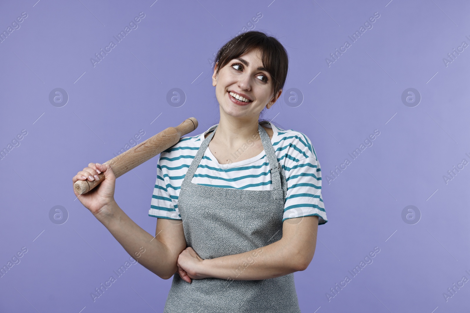 Photo of Happy woman with rolling pin on violet background