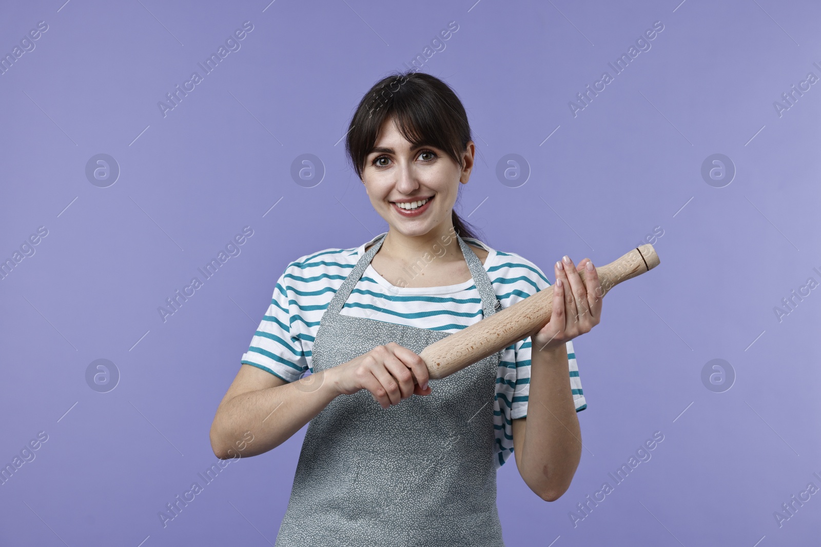 Photo of Happy woman with rolling pin on violet background