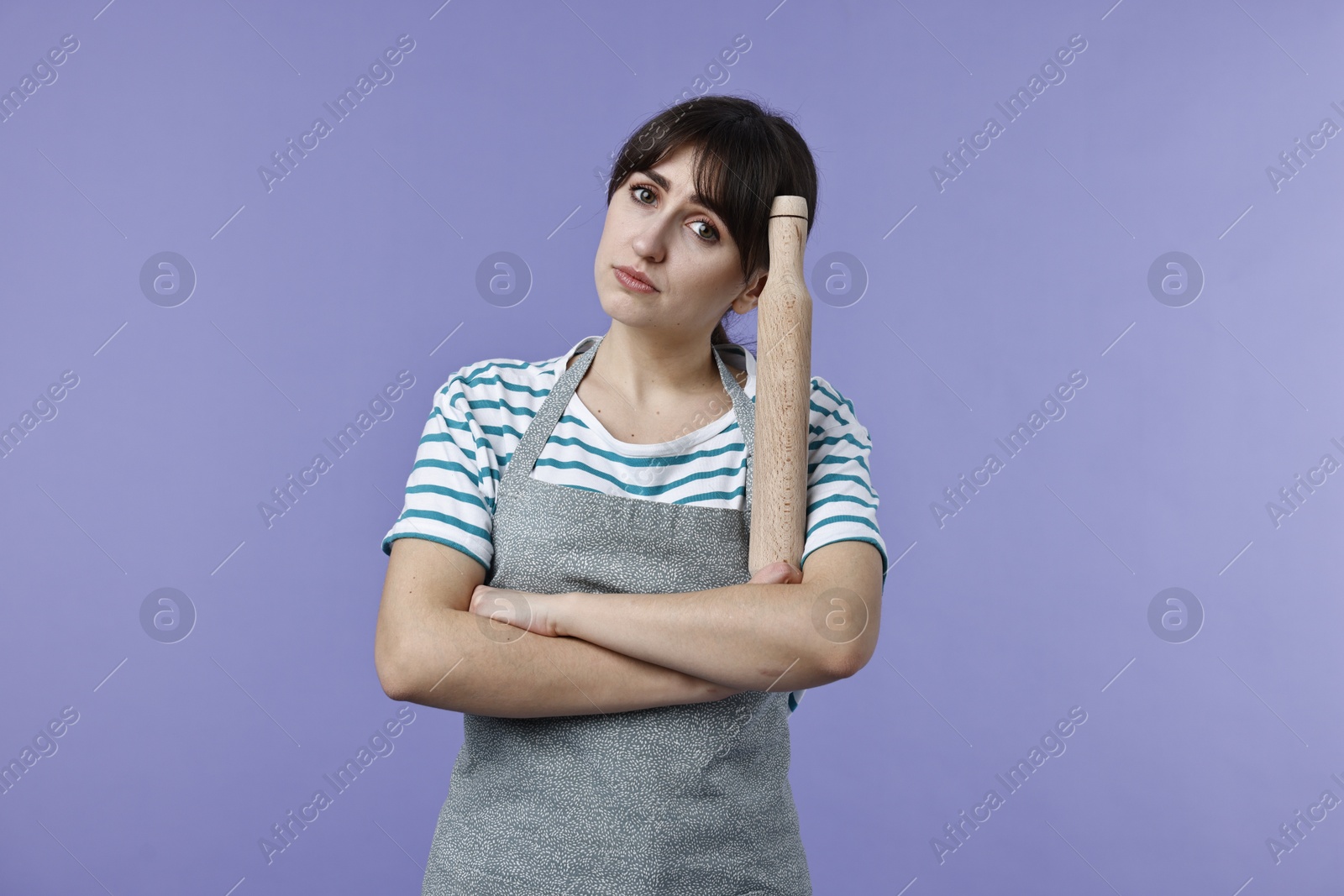 Photo of Upset woman with rolling pin on violet background