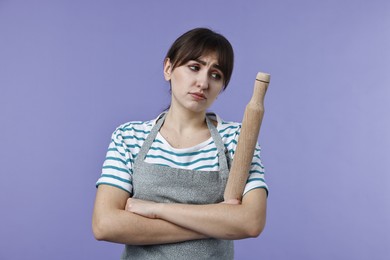 Photo of Upset woman with rolling pin on violet background