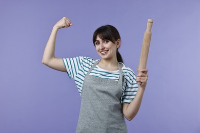 Photo of Woman with rolling pin showing strength on violet background