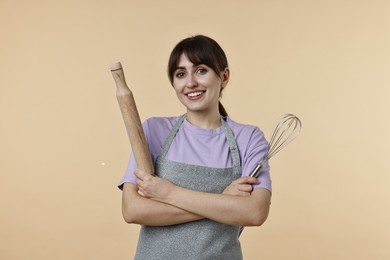 Photo of Woman with rolling pin and whisk on beige background