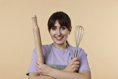 Photo of Woman with rolling pin and whisk on beige background