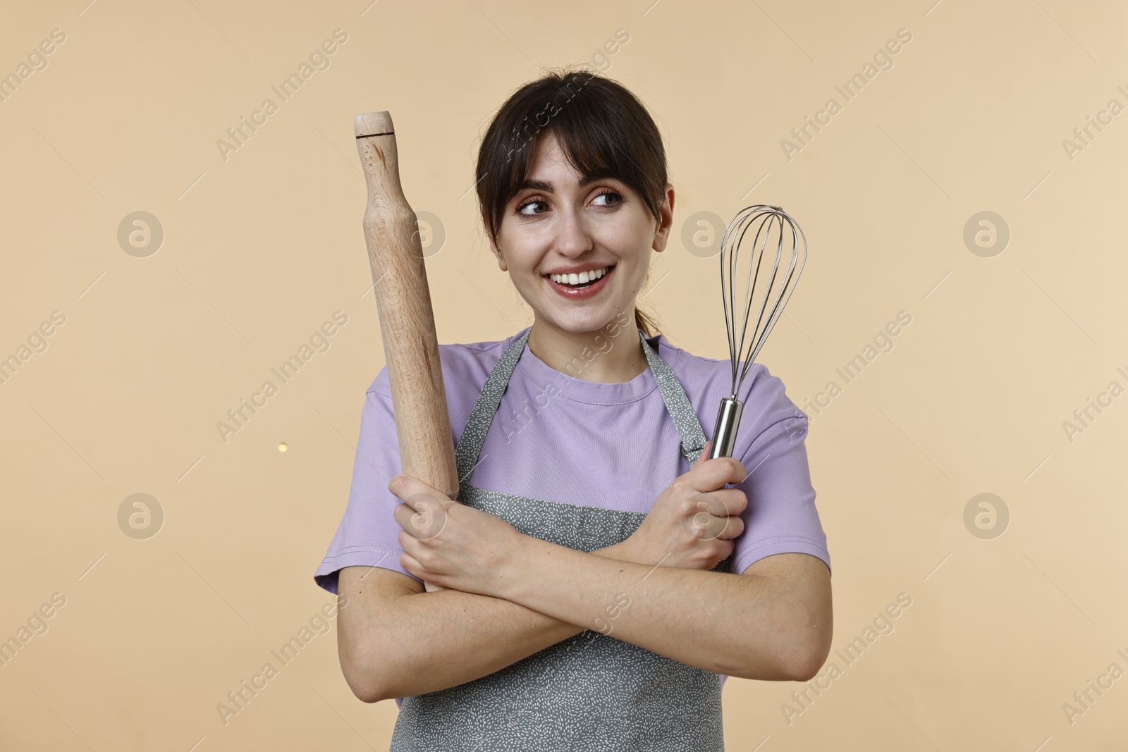 Photo of Woman with rolling pin and whisk on beige background