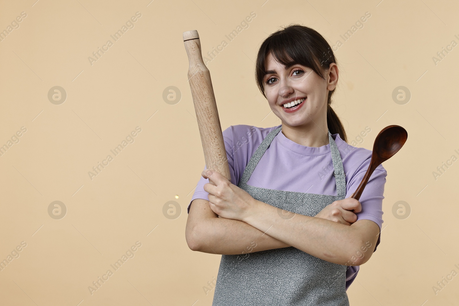 Photo of Woman with rolling pin and spoon on beige background. Space for text