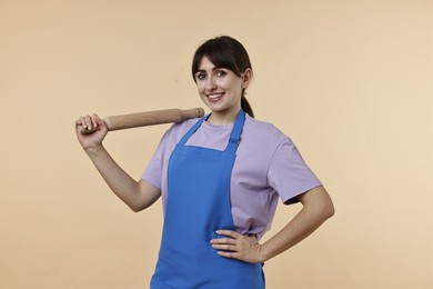 Photo of Happy woman with rolling pin on beige background