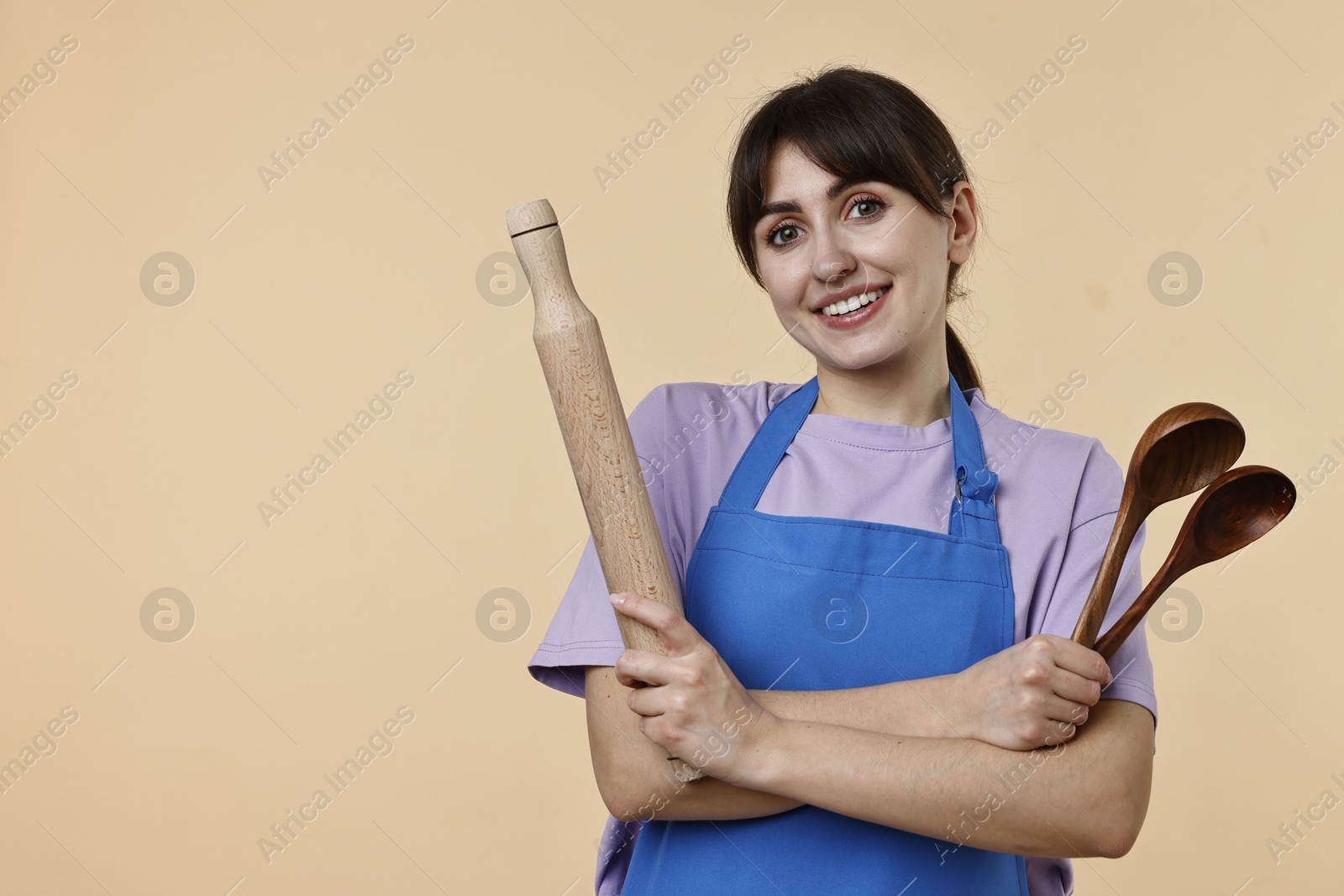 Photo of Woman with kitchen utensils on beige background. Space for text