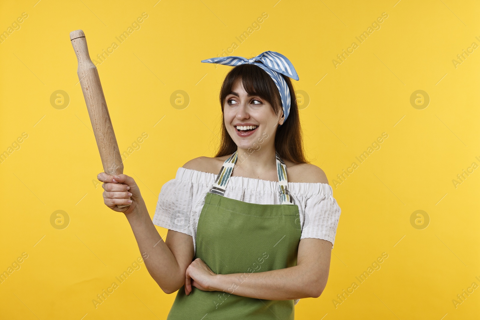 Photo of Happy woman with rolling pin on yellow background