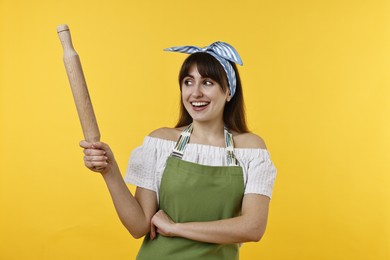 Photo of Happy woman with rolling pin on yellow background