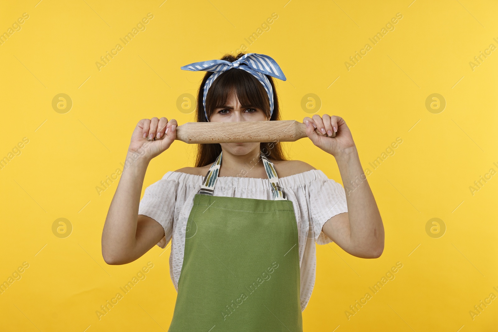 Photo of Angry woman with rolling pin on yellow background