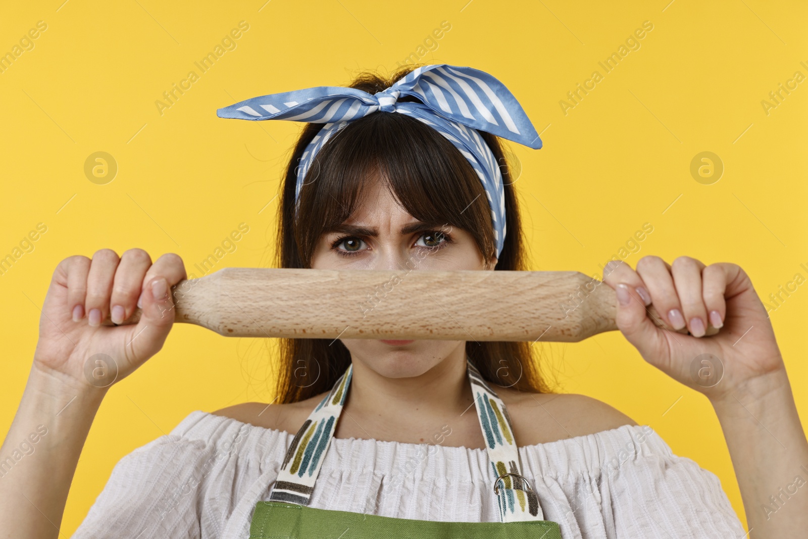 Photo of Angry woman with rolling pin on yellow background