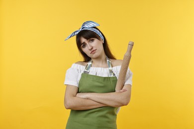 Photo of Upset woman with rolling pin on yellow background