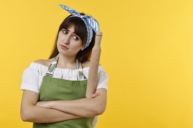 Photo of Upset woman with rolling pin on yellow background. Space for text