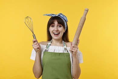 Photo of Excited woman with rolling pin and whisk on yellow background