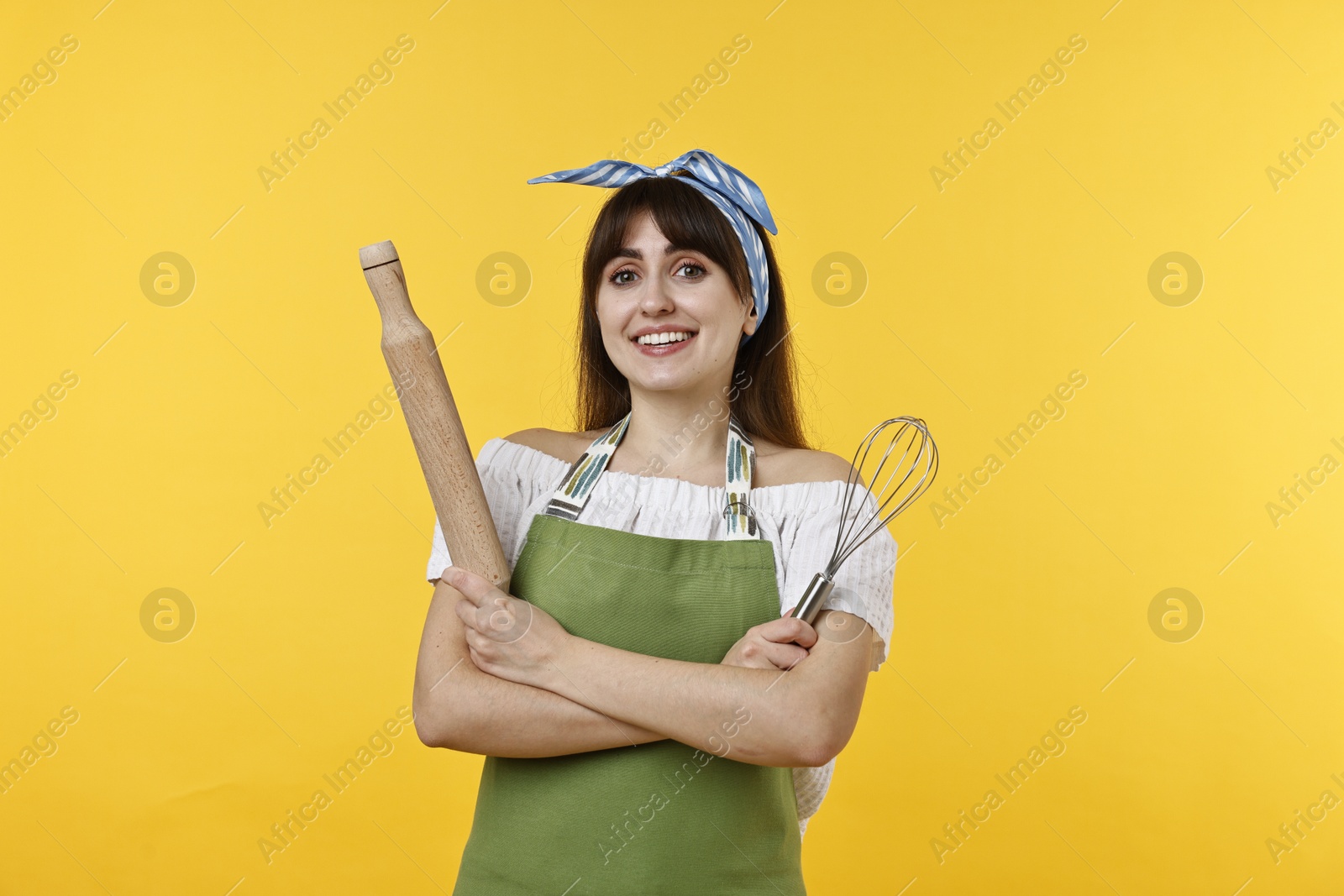 Photo of Woman with rolling pin and whisk on yellow background