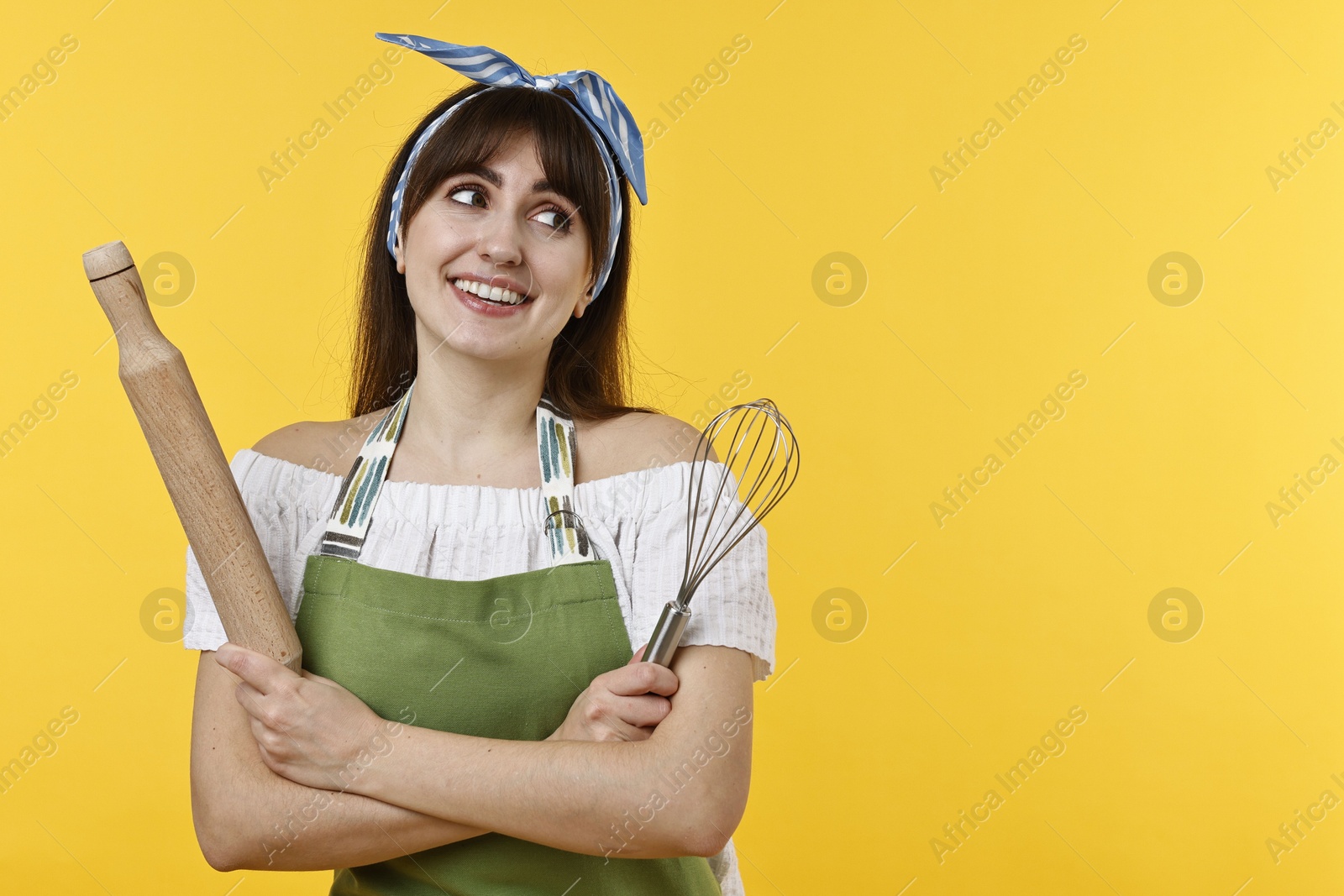 Photo of Woman with rolling pin and whisk on yellow background. Space for text