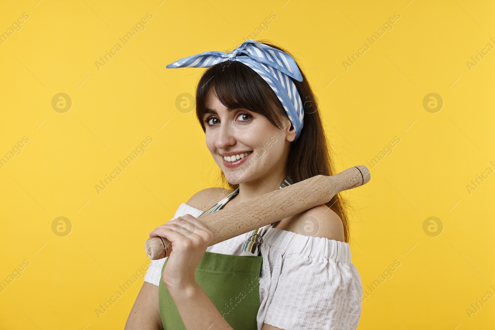 Photo of Happy woman with rolling pin on yellow background