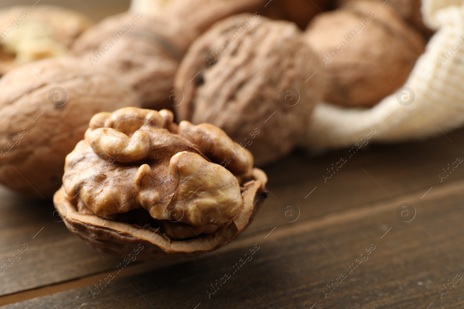 Photo of Fresh walnuts with shells on wooden table, closeup. Space for text