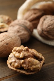 Photo of Fresh walnuts with shells on wooden table, closeup