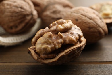 Photo of Fresh walnuts with shells on wooden table, closeup