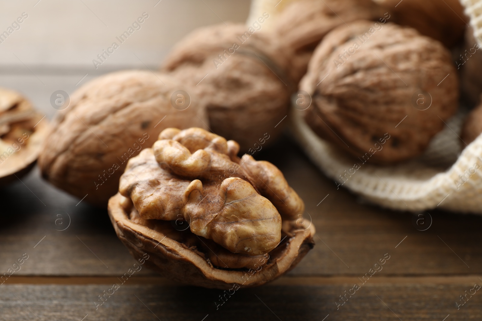 Photo of Fresh walnuts with shells on wooden table, closeup