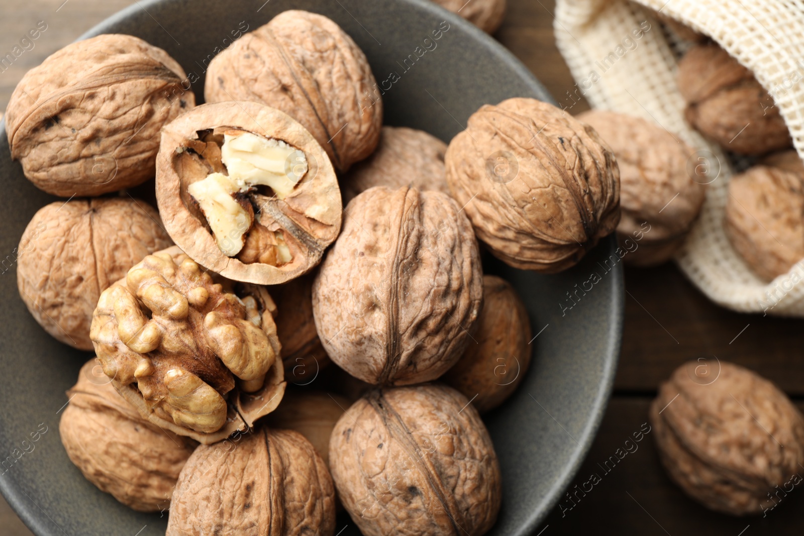 Photo of Fresh walnuts in bowl and bag on table, flat lay