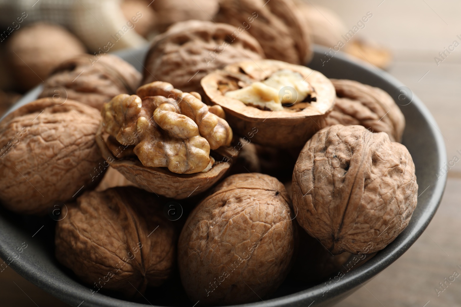 Photo of Fresh walnuts in bowl on table, closeup