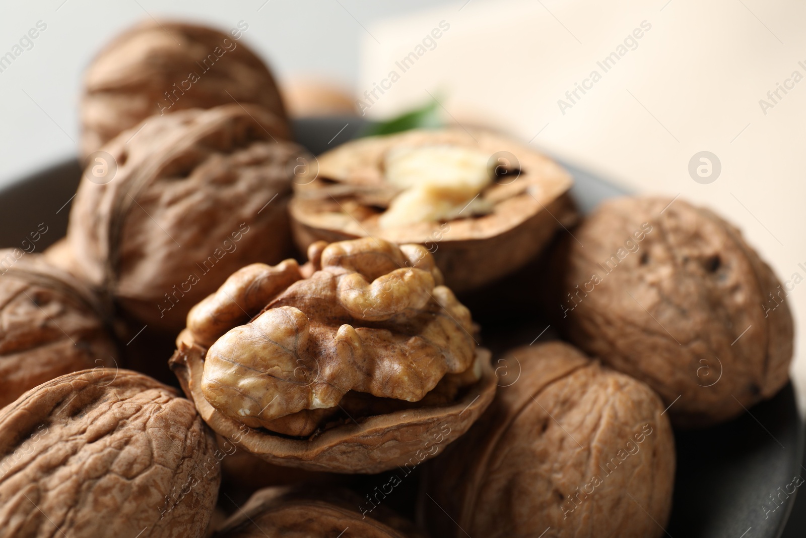 Photo of Fresh walnuts in bowl on light table, closeup