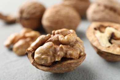 Photo of Fresh walnuts with shells on gray table, closeup