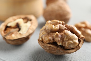 Photo of Fresh walnuts with shells on gray table, closeup. Space for text