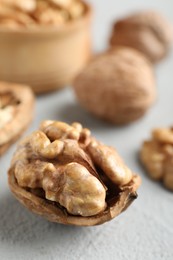 Photo of Fresh walnuts with shells on gray table, closeup