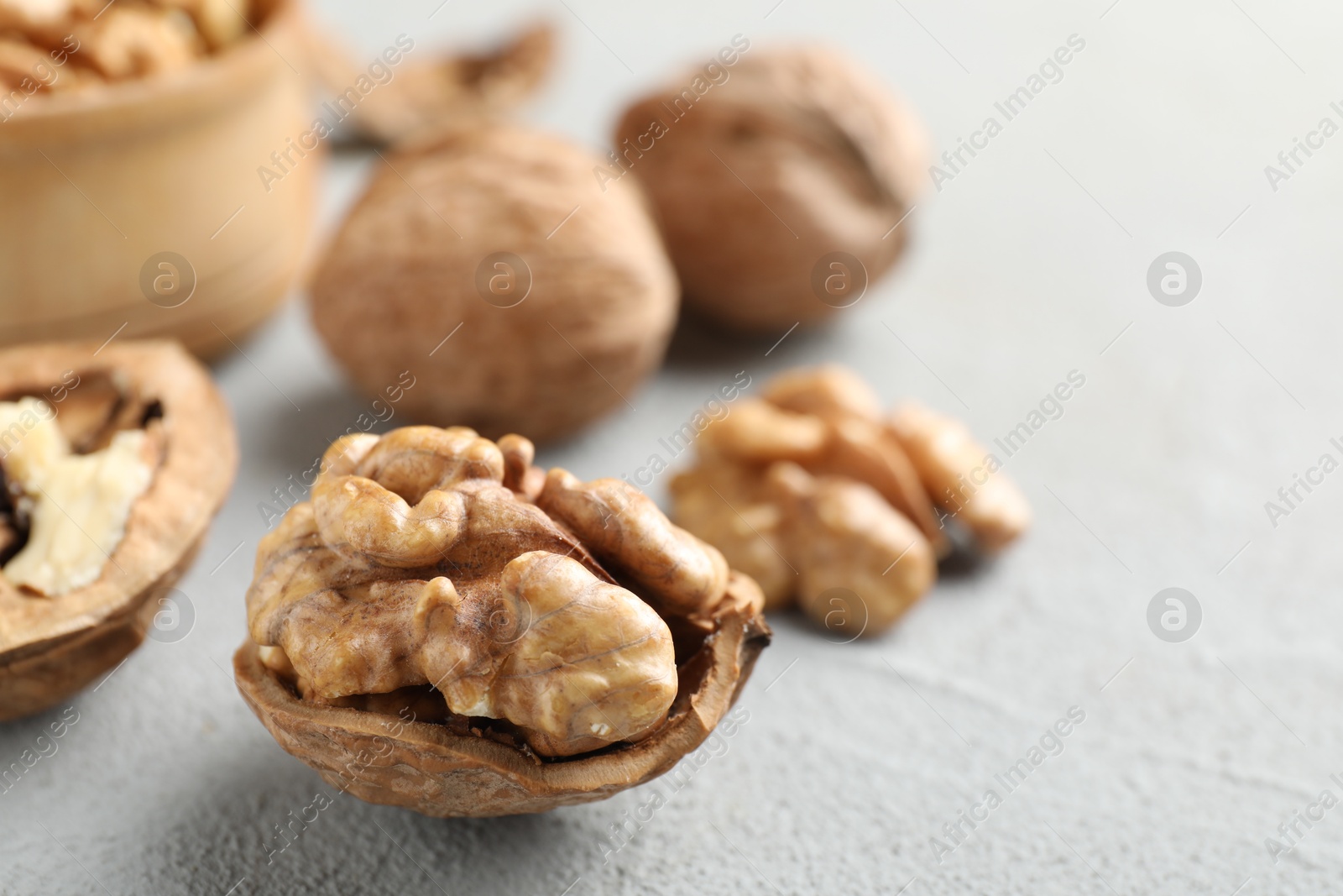 Photo of Fresh walnuts with shells on gray table, closeup. Space for text