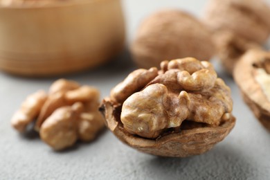 Photo of Fresh walnuts with shells on gray table, closeup. Space for text