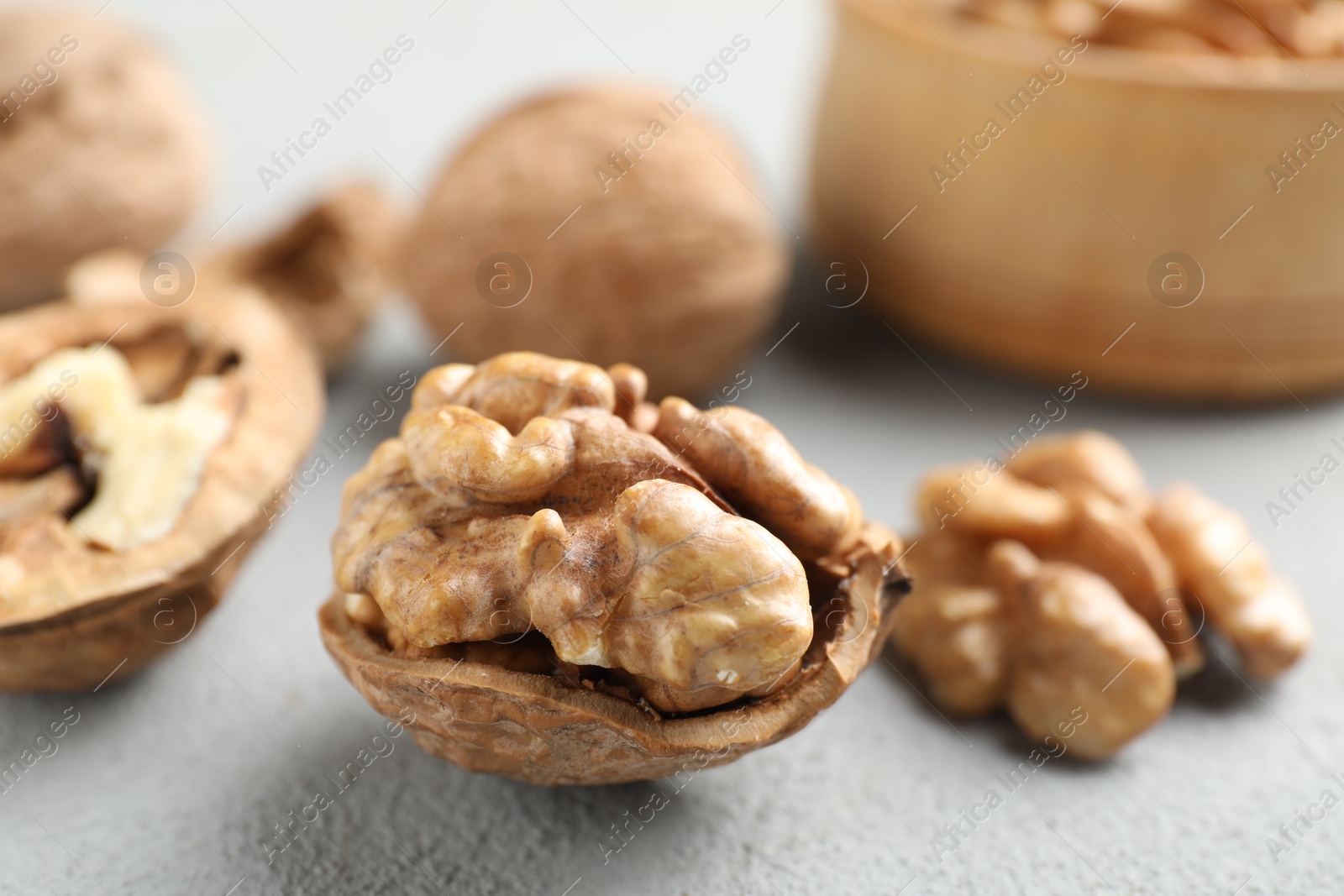 Photo of Fresh walnuts with shells on gray table, closeup