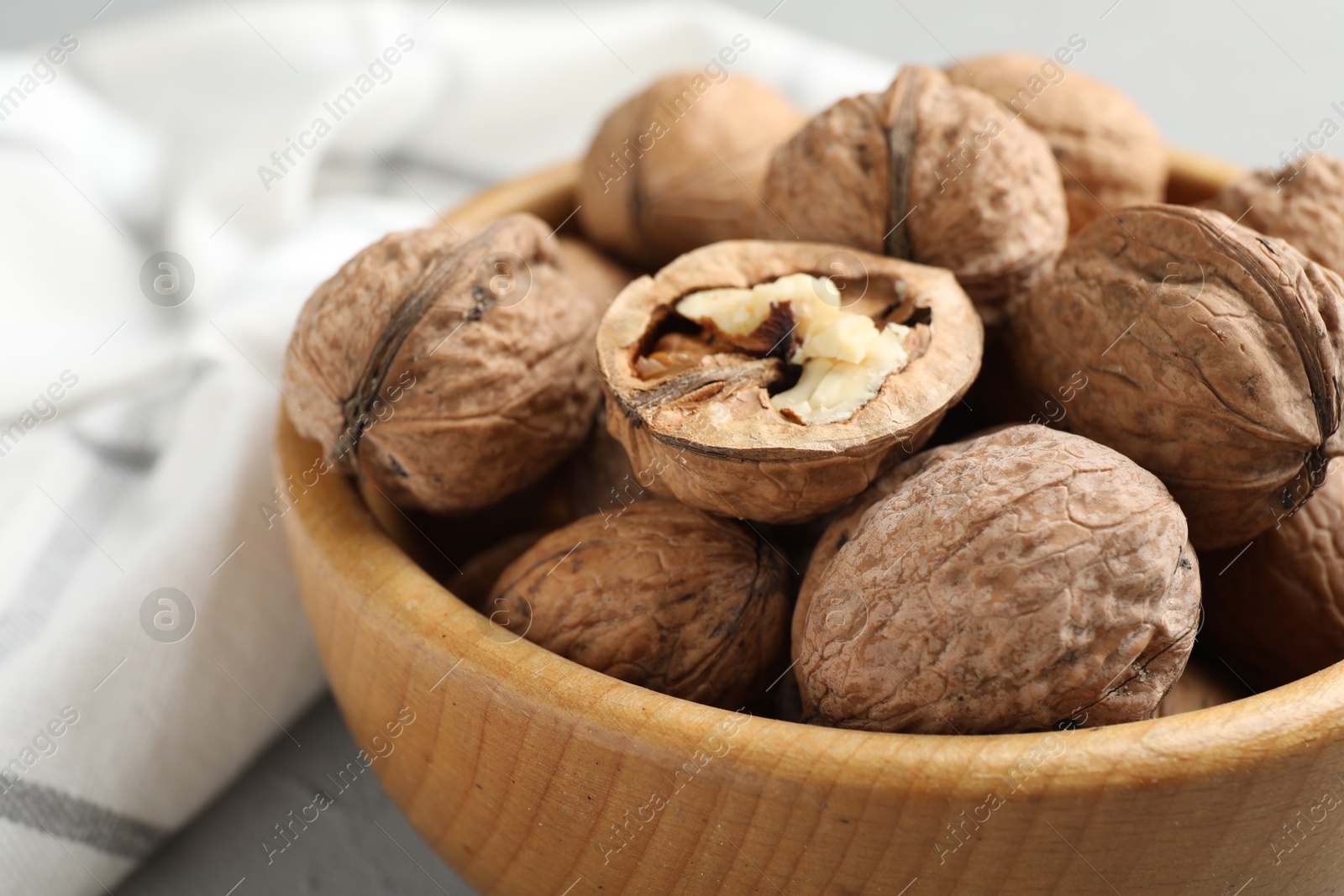 Photo of Fresh walnuts in bowl on table, closeup