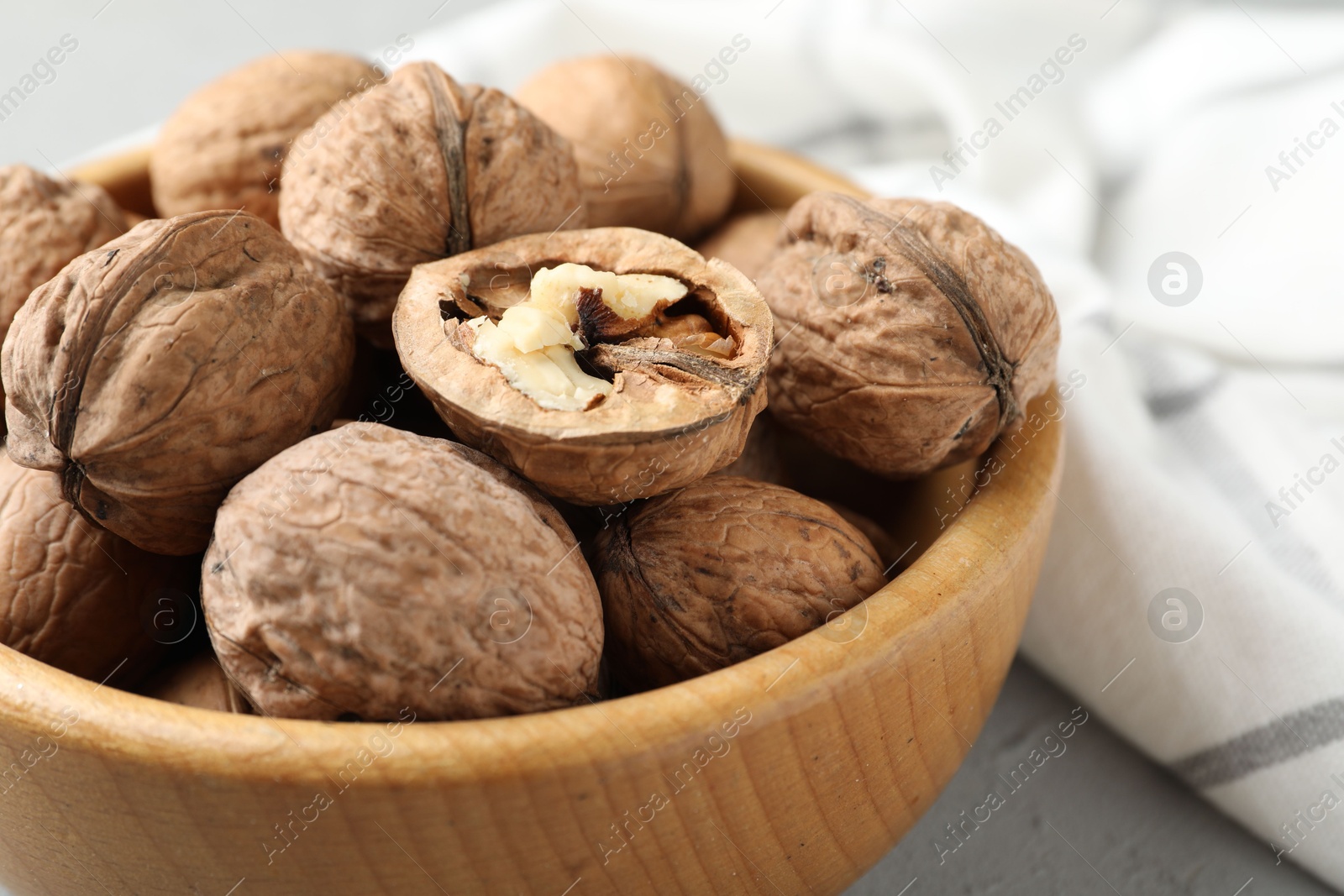 Photo of Fresh walnuts in bowl on table, closeup